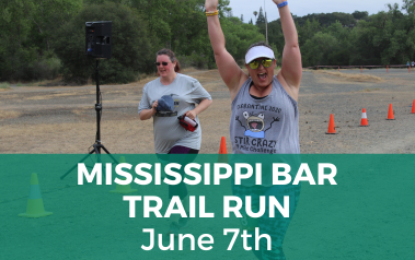 Trail Run - June - Photo of woman finishing the race with her arms in the air