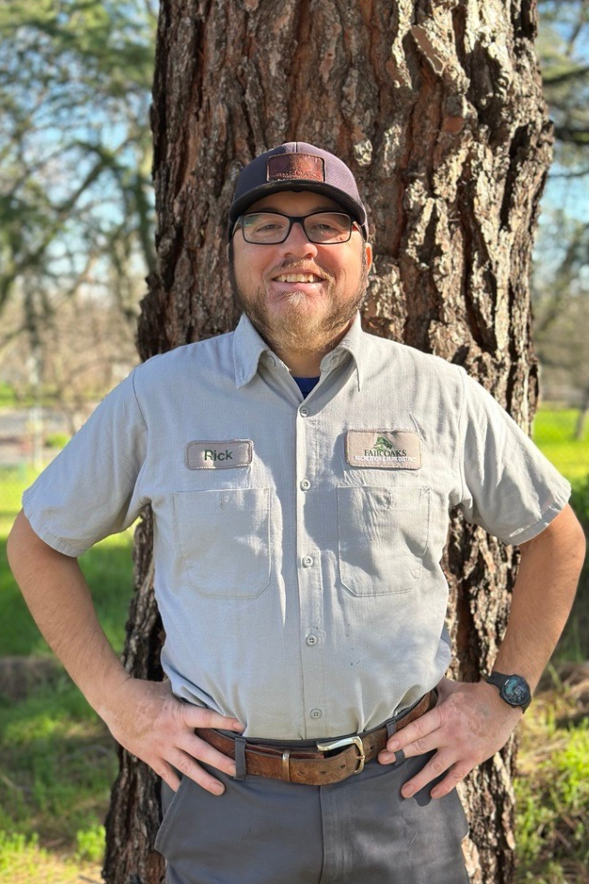photo of a park worker standing in front of a tree