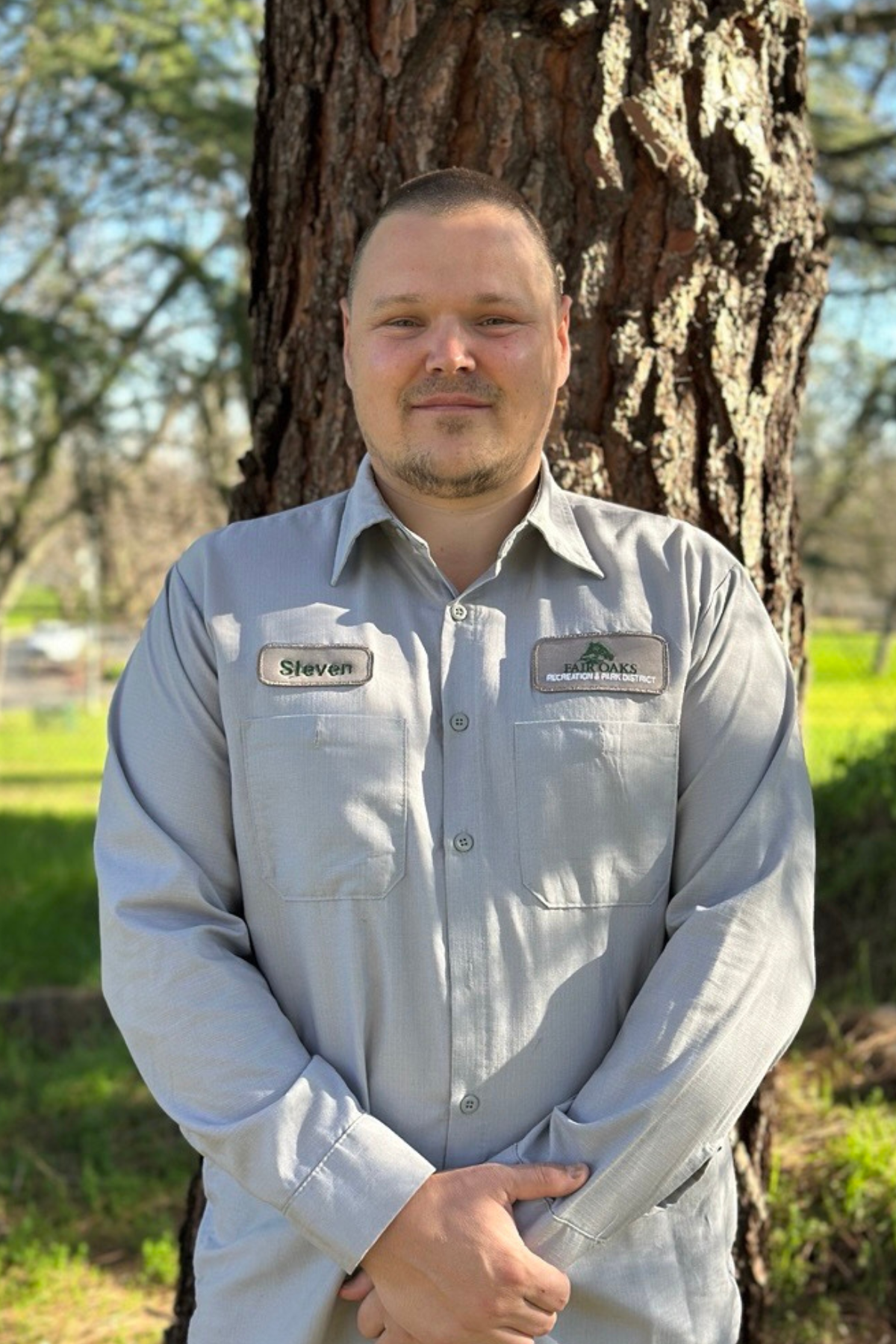 photo of a park worker standing in front of a tree